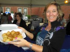 Friendly volunteer serving Loukoumades at The Big Greek Food Fest in Niles