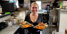 Friendly server with burgers at Niko's Red Mill Tavern in Woodstock